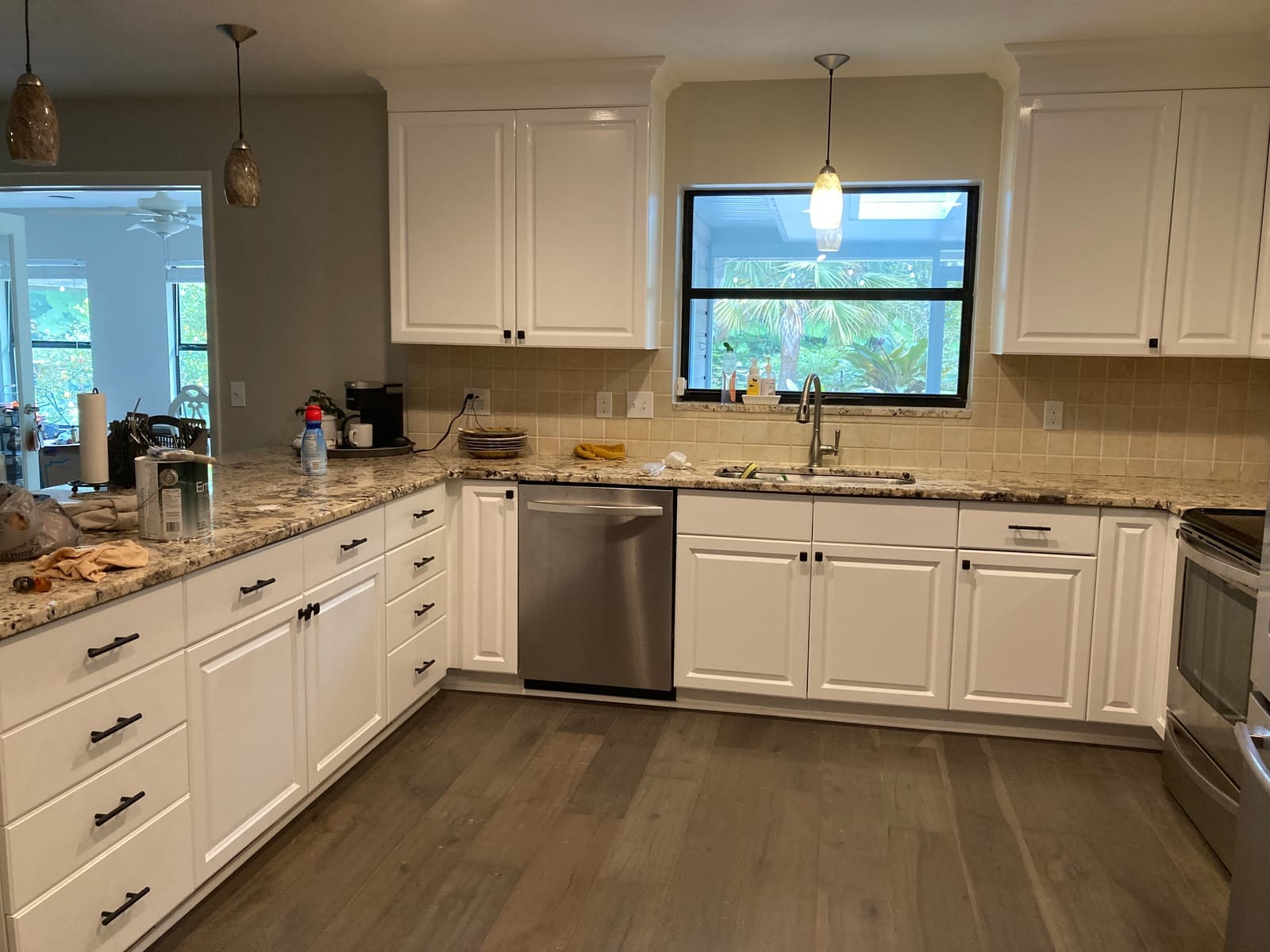 Kitchen cabinets refinished in brushed white enamel, clean counters under window light