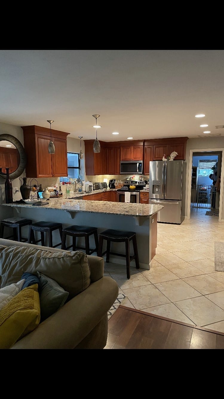 Kitchen cabinets before refinishing, original wood-tone doors and dated hardware