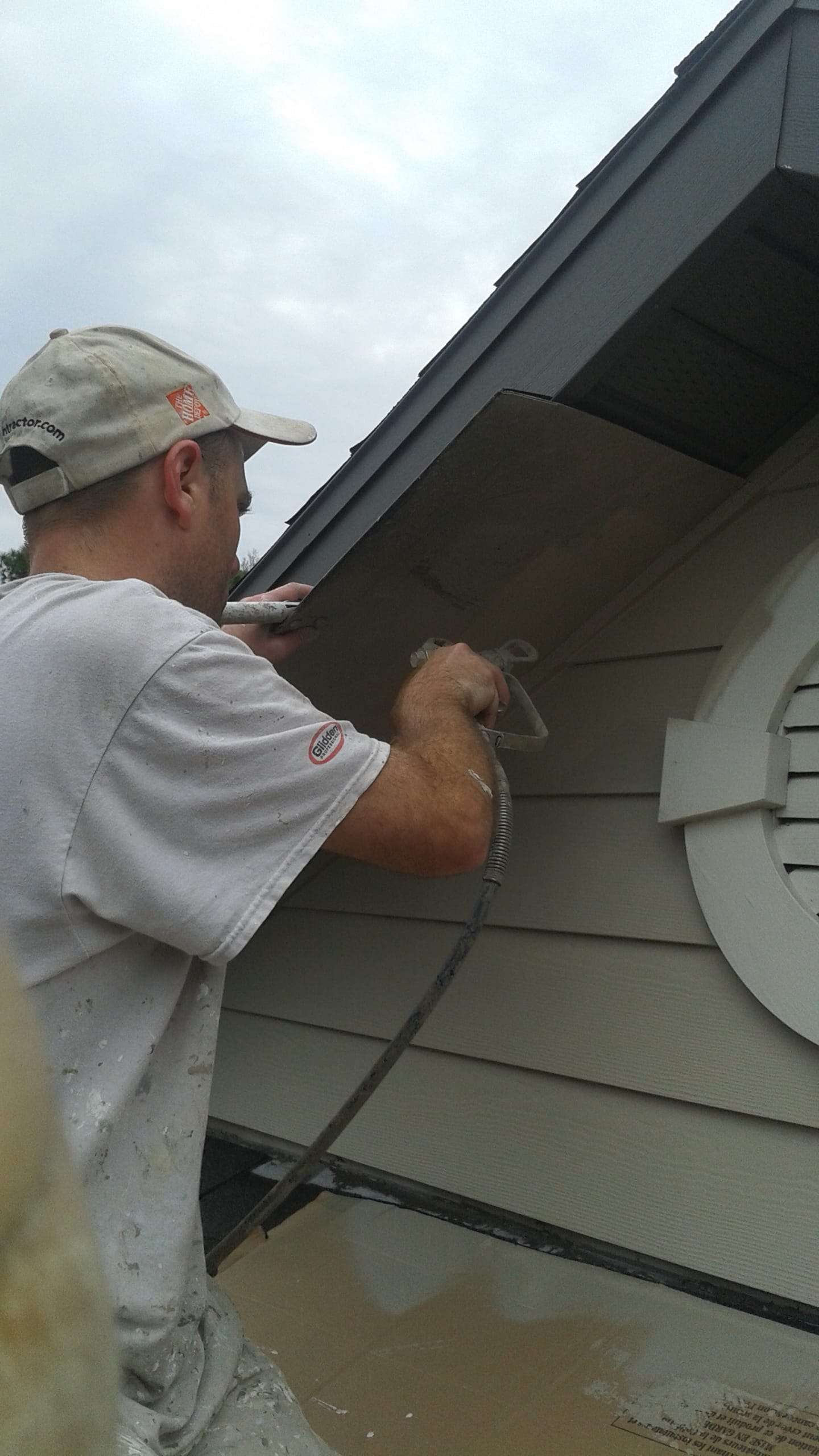 Christopher Combs, owner of A+ Painting and Repair, spraying a home soffit on a jobsite