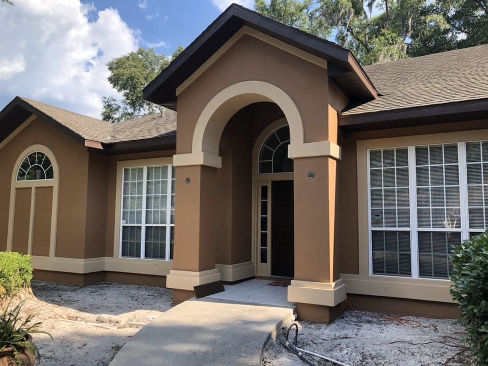 Stucco home with arched entry, warm brown two-tone paint